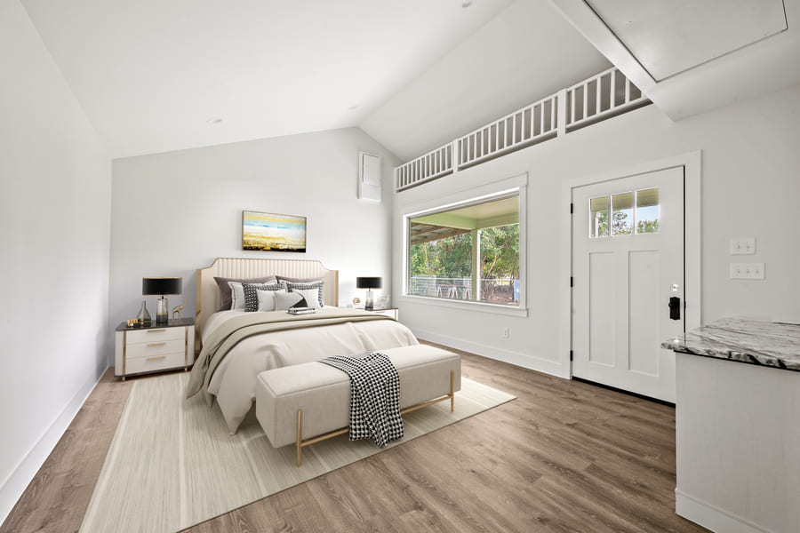 Bright, modern bedroom with a beige bed, nightstands with black lamps, large window, white door, and wood flooring.